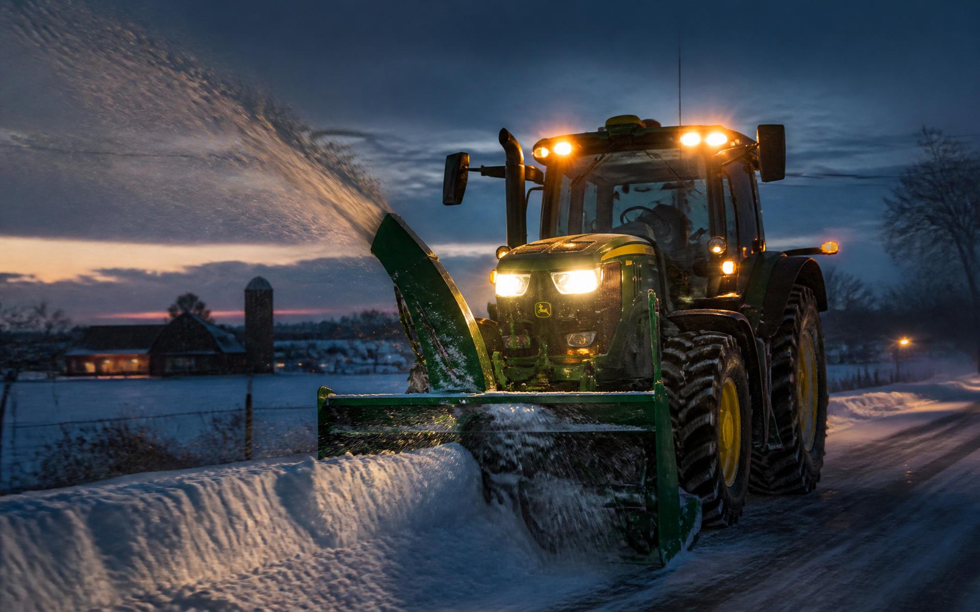 Tracteur en travail de déneigement au crépuscule dans un paysage agricole